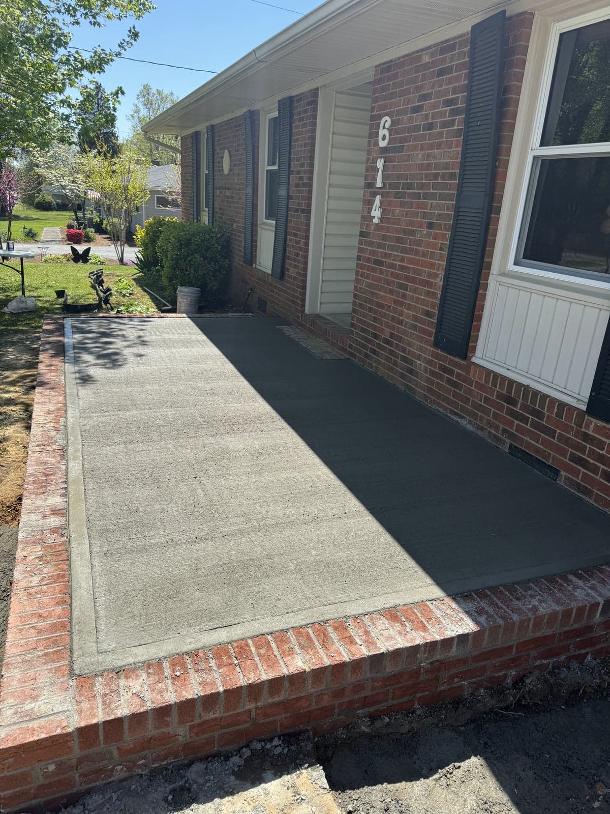 Concrete patio extension with brick border