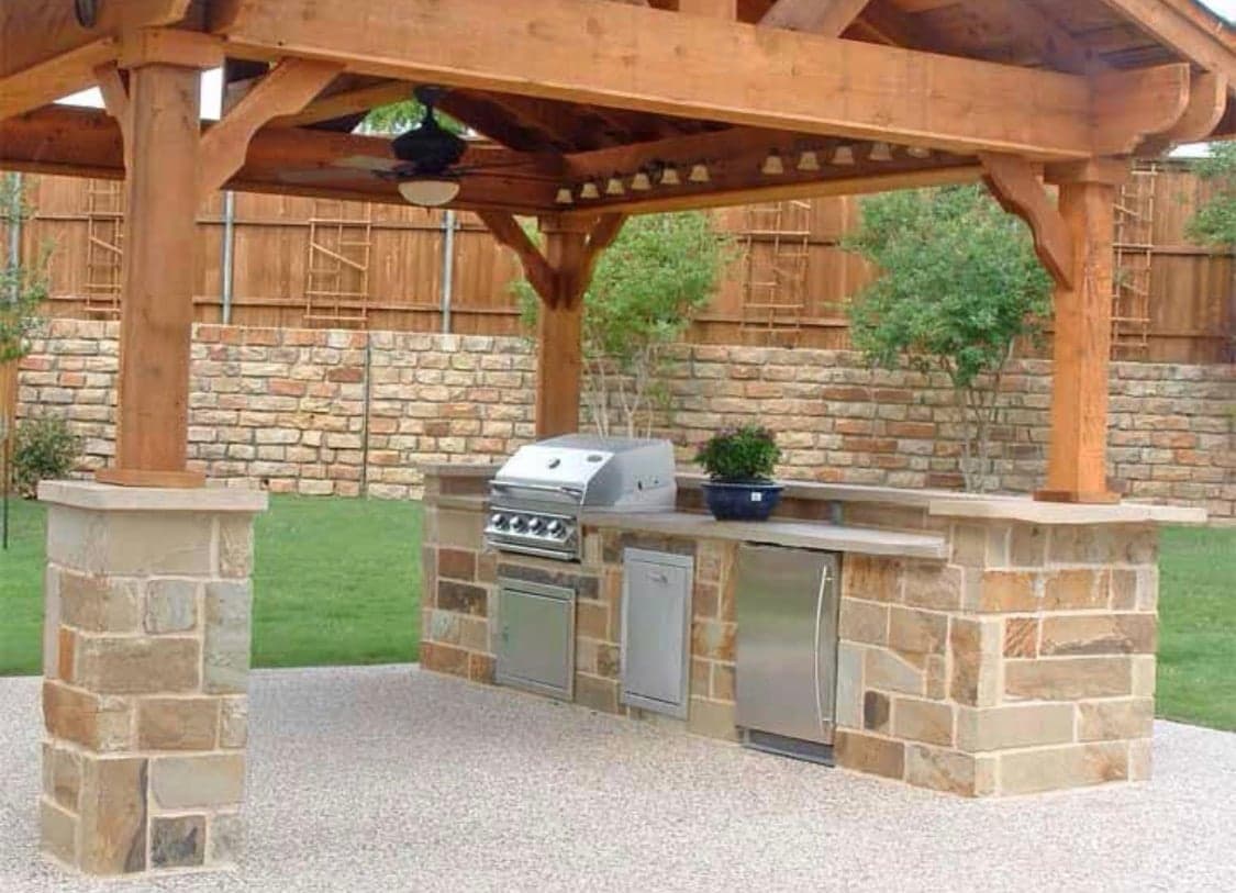 Stone-veneer outdoor kitchen under a timber pergola